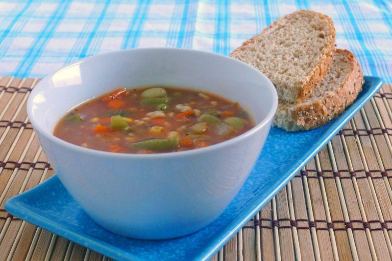 white bowl of vegetable soup with whole wheat bread