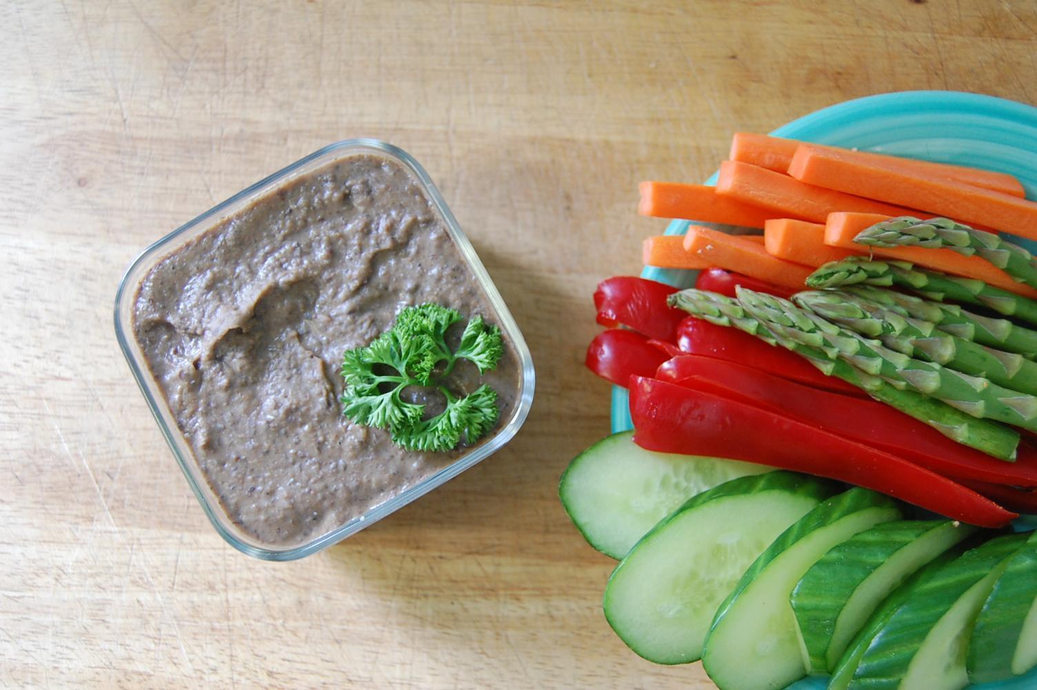 black bean dip bowl with raw veggie sticks, cucumber, pepper, asparagus, carrots