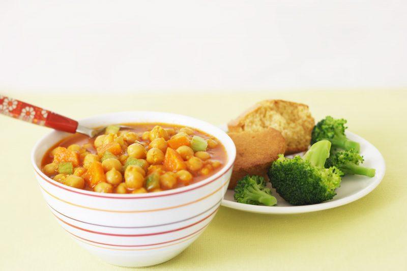 bowl of chickpea chowder with broccoli and cornbread on the side