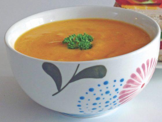 bowl of carrot squash coconut soup with parsley garnish