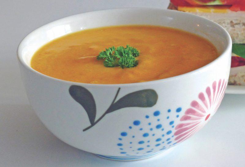 bowl of carrot squash coconut soup with parsley garnish