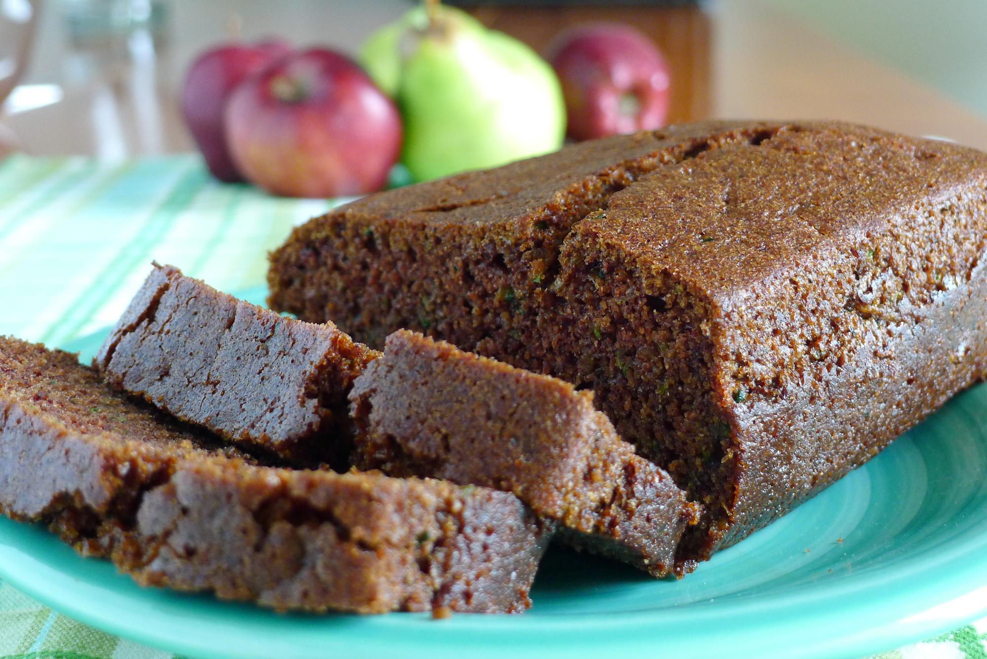 zucchini loaf half sliced with apples in background