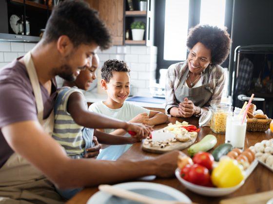 Healthy food at home. Happy black family in the kitchen having fun and cooking together