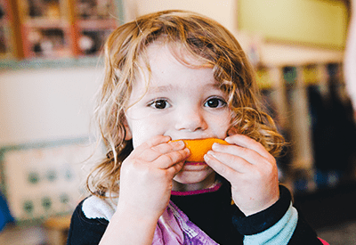 young girl eating orange slice