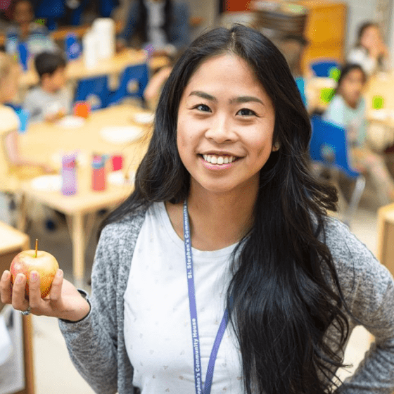 female ECE in classroom holding apple