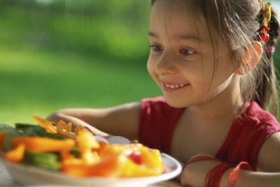 young girl looking excitedly at plates of veggies