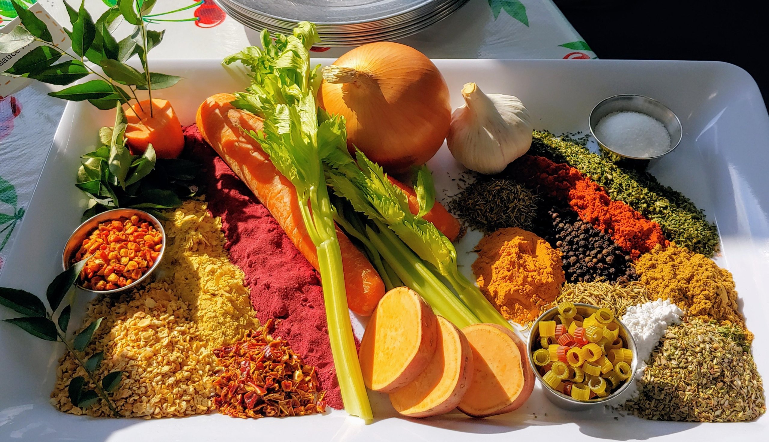 tray of soup ingredients including spices, celerym carrot, onion, garlic, sweet potato and pasta