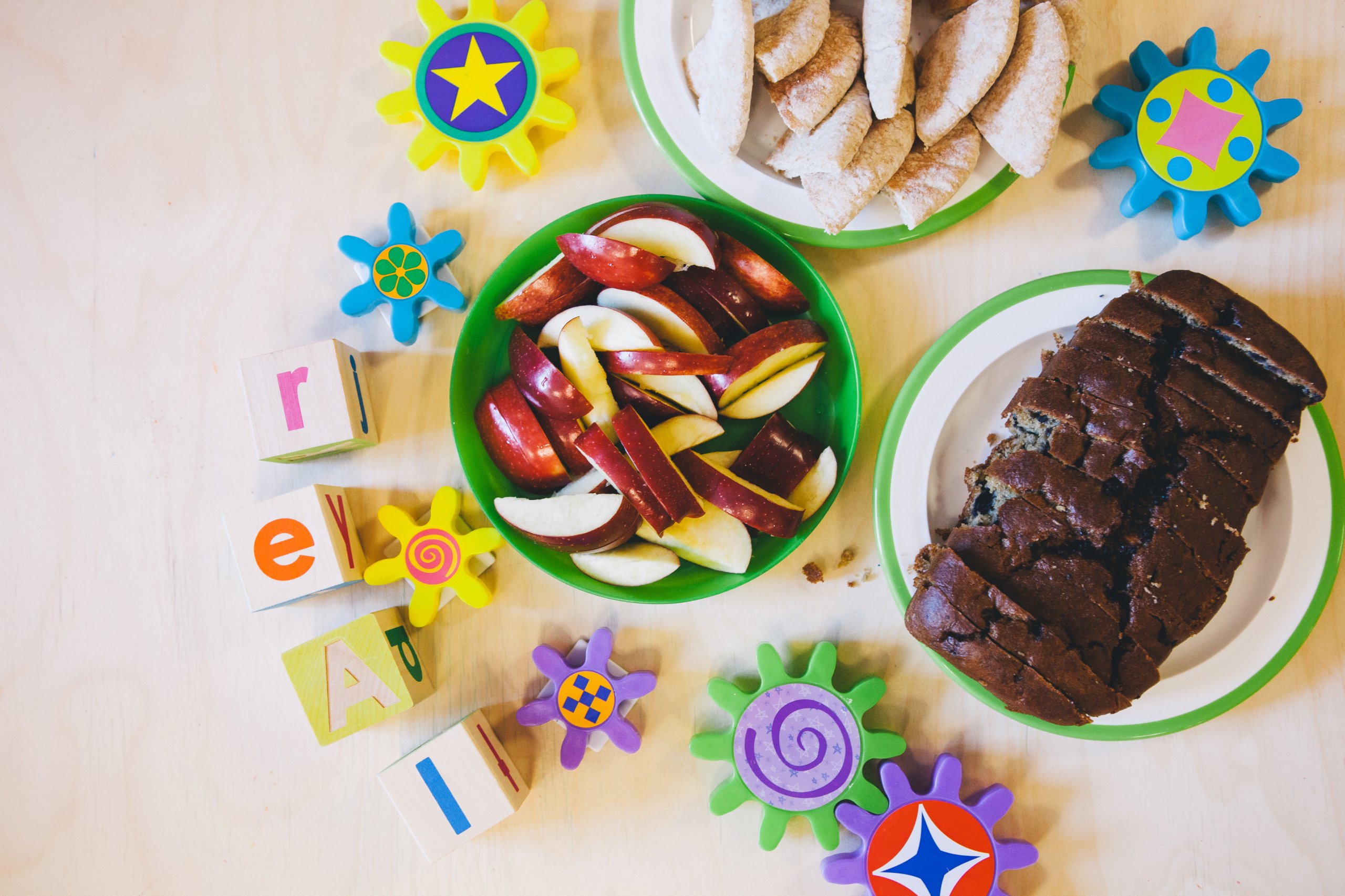 table with toy blocks, apple slices, blueberry loaf and pita bread