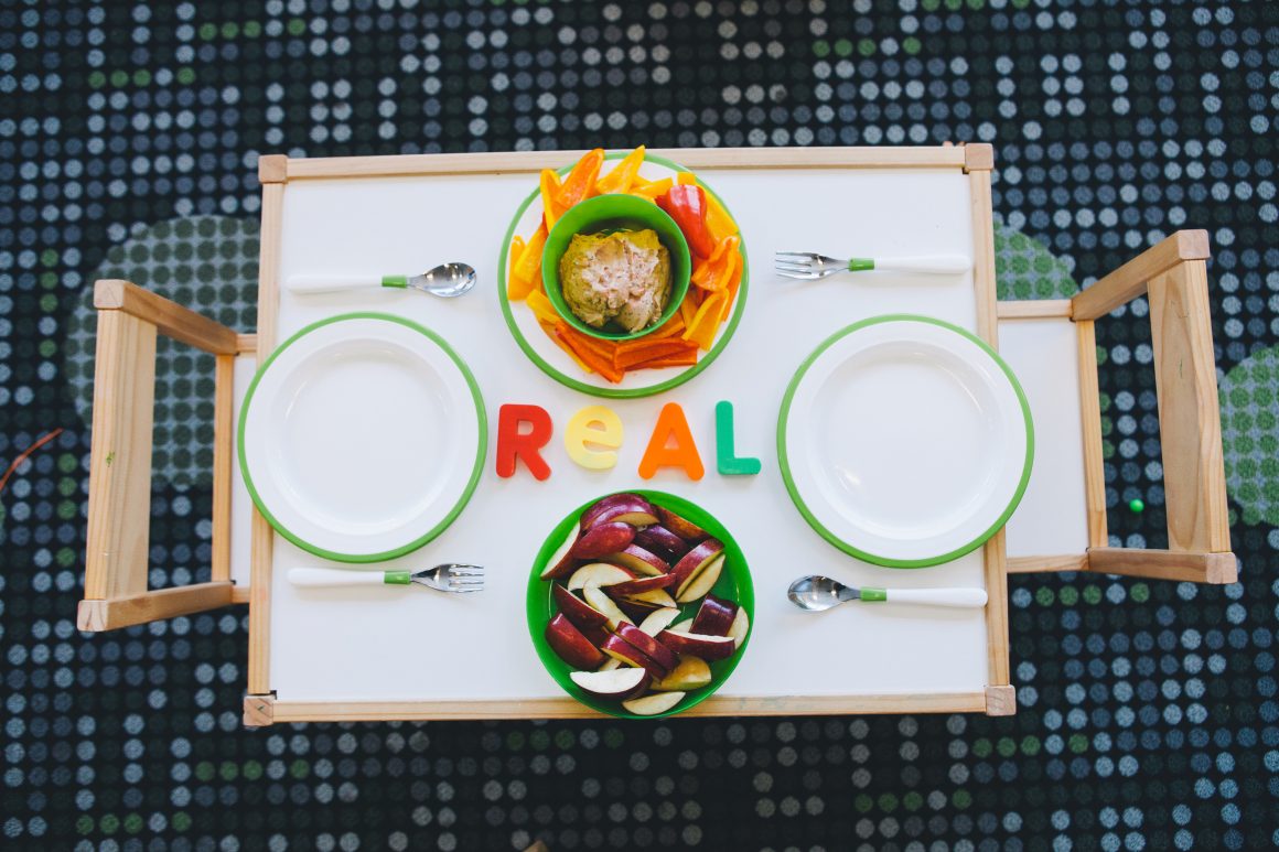 children's table and chairs with apple slices and hummus and pepper slices