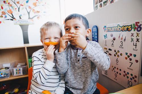 two young boys enjoying orange slices at daycare