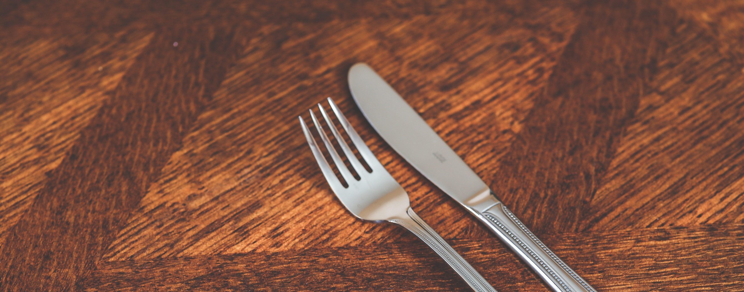 dark wood table with silver fork and knife