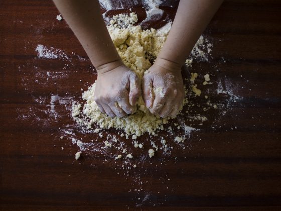 dark wood table with child's hands kneading dough
