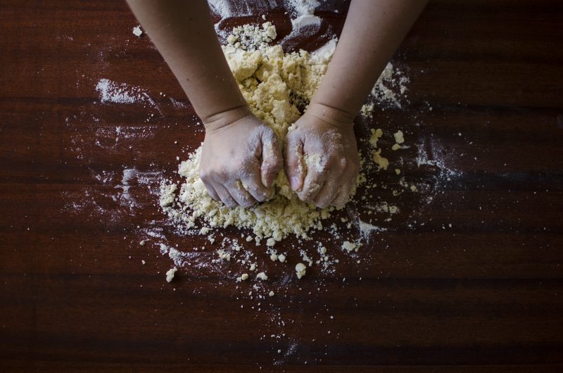 dark wood table with child's hands kneading dough