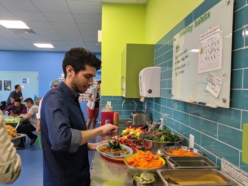 man in staff room plating spread of healthy food