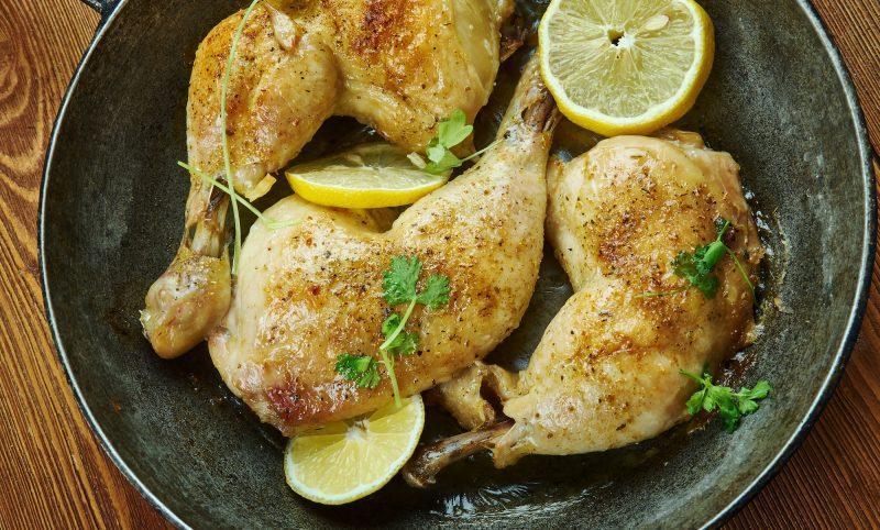 plate of roasted chicken legs and lemon slices