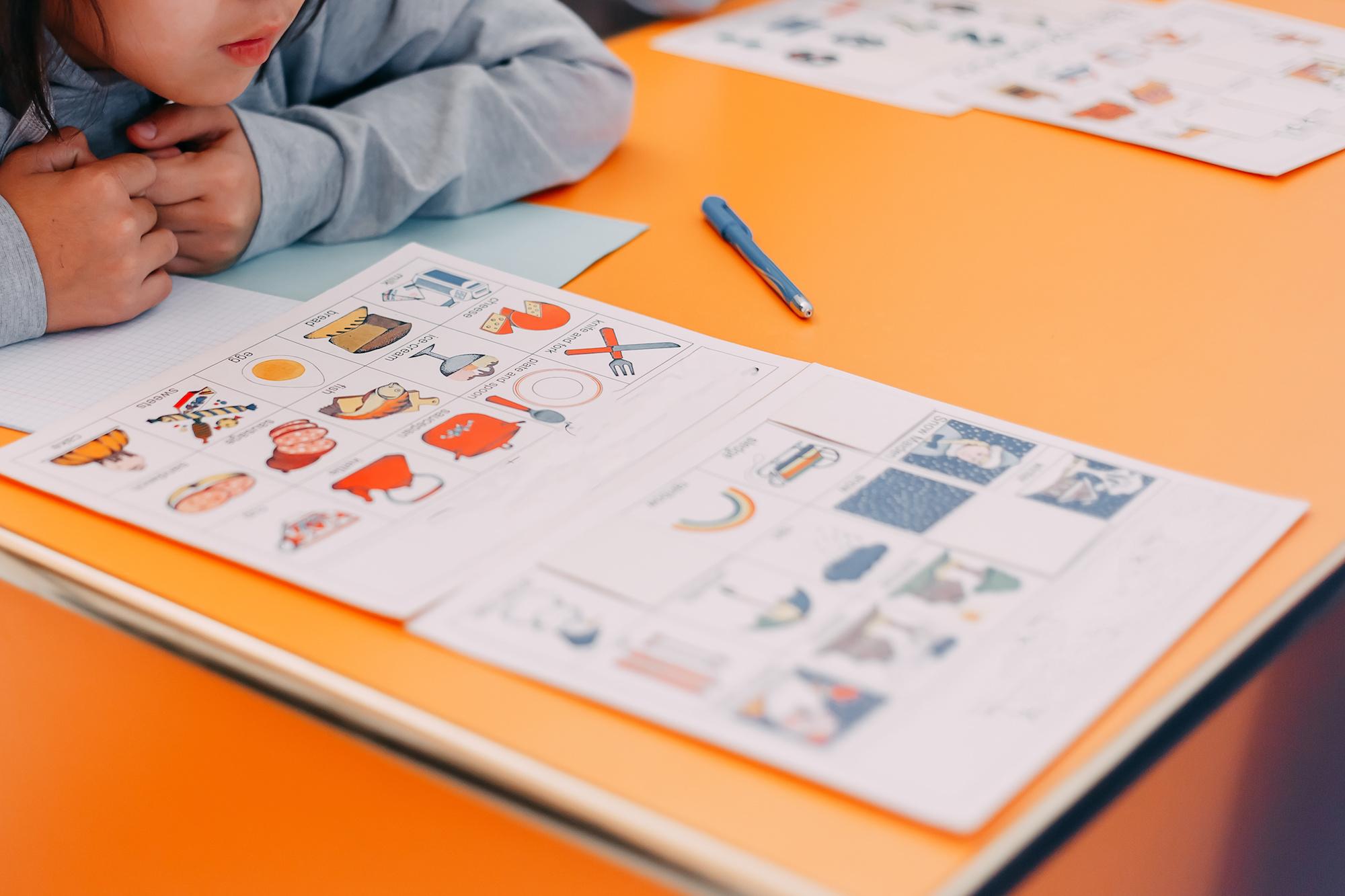 children hands touching white cards of letters numbers and pictures for little kids on the blue table. Time to learn. Education concept. Top view.