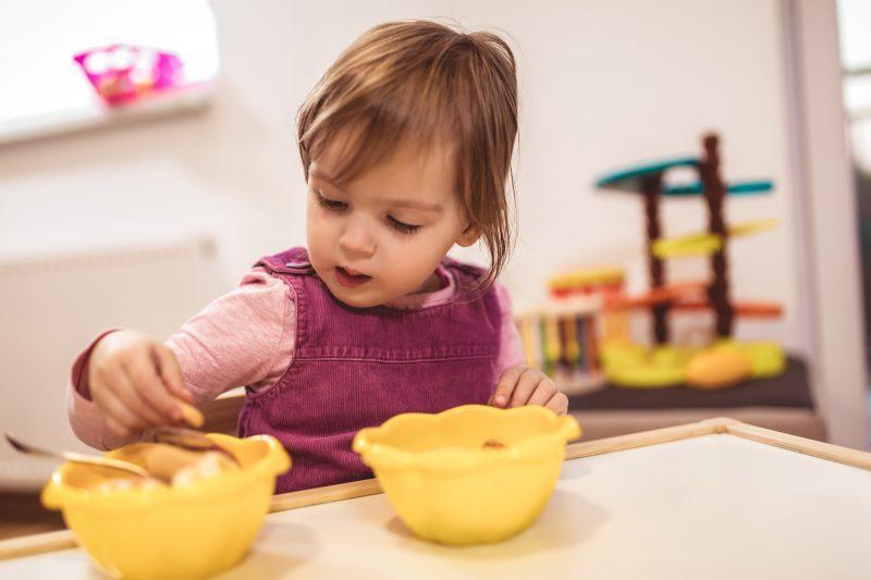 toddler at table with 2 yellow bowls