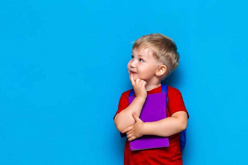 young boy with purple book in front of blue background