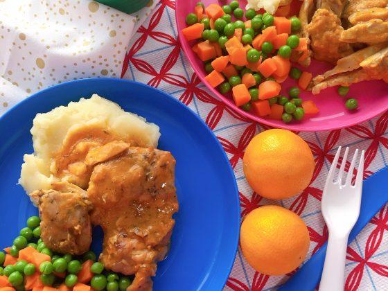 blue and pink plates of peas & carrots with mashed potatoes and chicken with gravy, 2 clementines