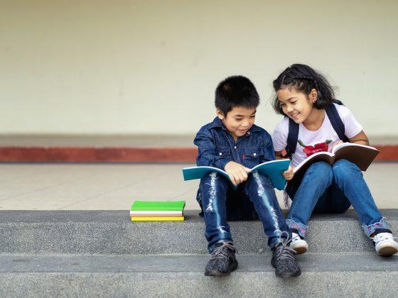 young boy and girl sitting on steps reading books