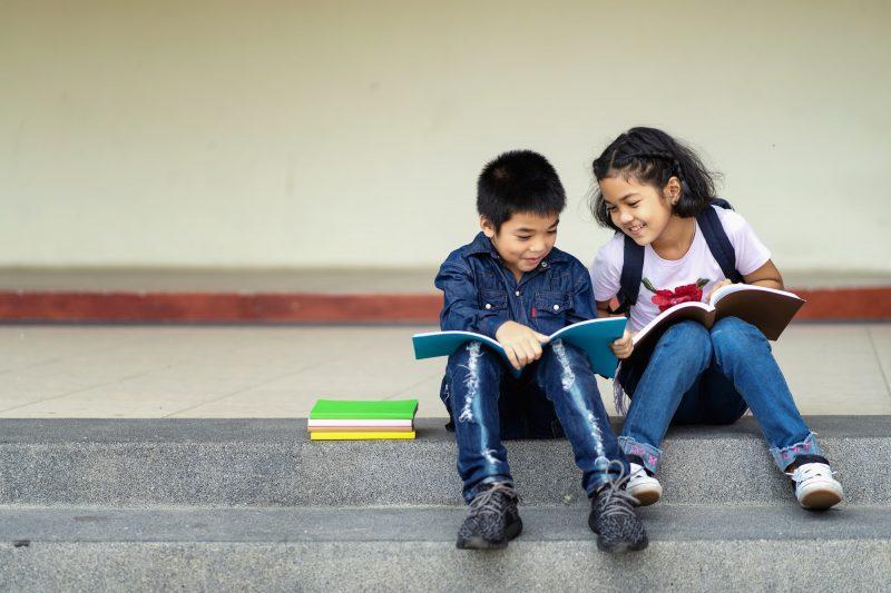 young boy and girl sitting on steps reading books