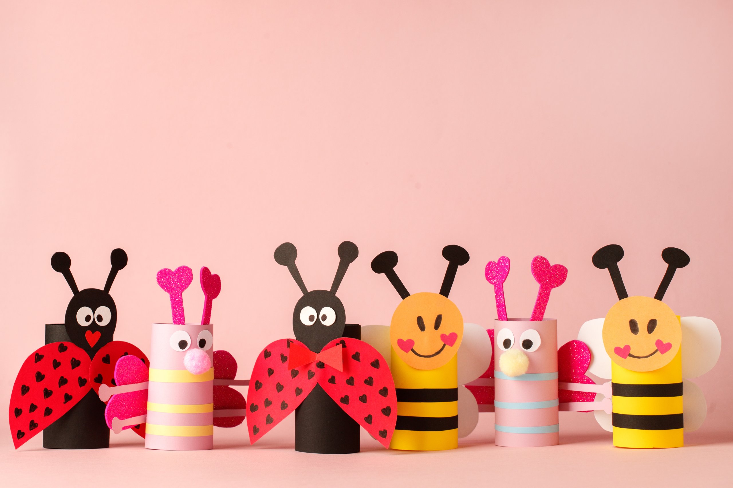 Paper toy insect for valentine romance baby shower, birthday party. Easy crafts for kids on pink background, copy space, die creative idea from toilet tube roll, recycle reuse eco