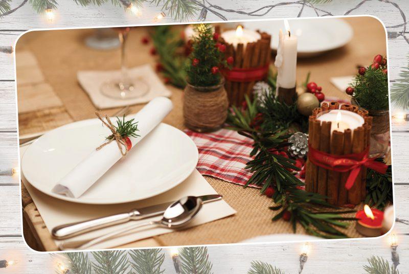 christmas decorated dinner table with plate, cutlery and cinnamon candle