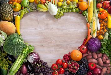 Assortment of fresh fruits and vegetables in heart shape on wooden background