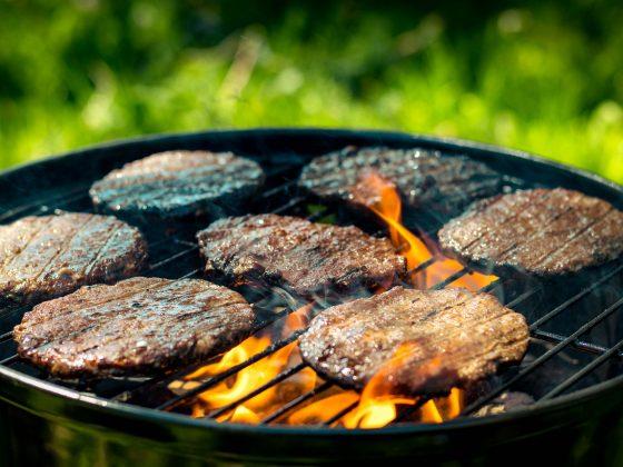 beef burgers on grill with flames