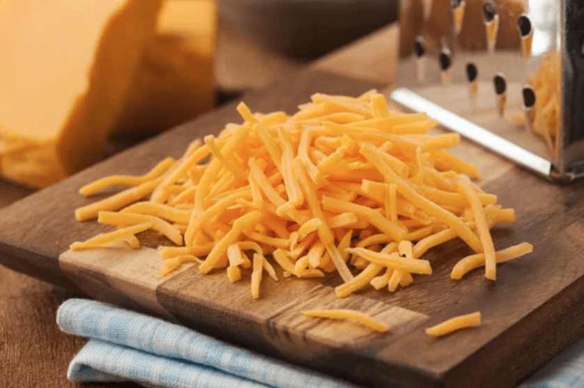 shredded cheddar on wooden board