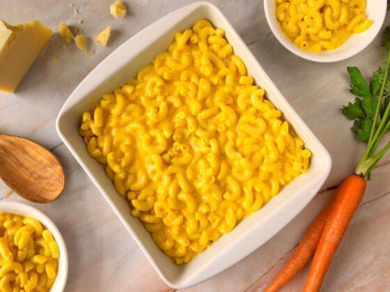 square white serving dish with macaroni and cheese, carrot and cheese block on the side