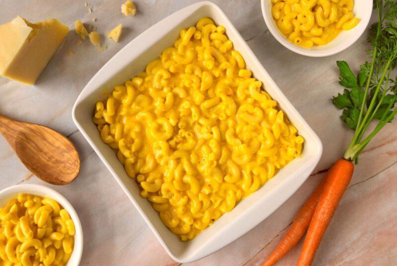 square white serving dish with macaroni and cheese, carrot and cheese block on the side