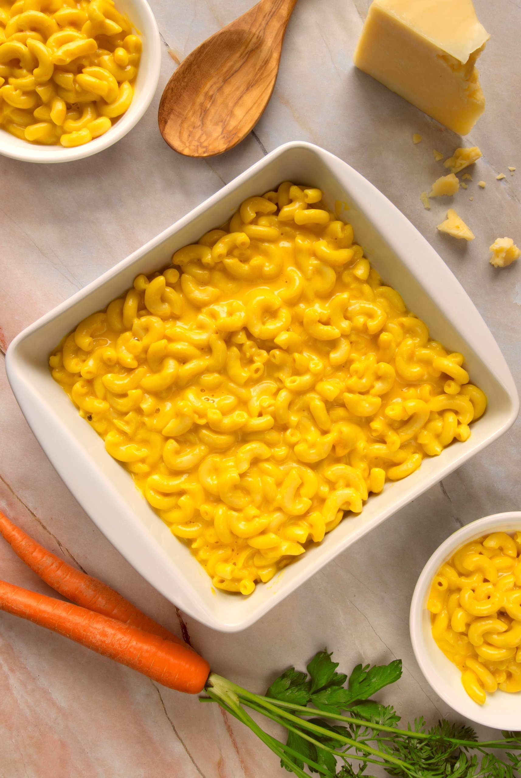 square white serving dish with macaroni and cheese, carrot and cheese block on the side