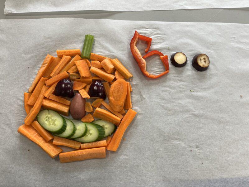 halloween veggie activity, jack o lantern face made of carrot, cucumber, eggplant and potato with boo in peppers