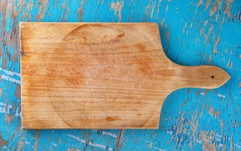 Cutting board on rustic wooden kitchen table as blank copy space for food, cooking and nutrition themes, top view
