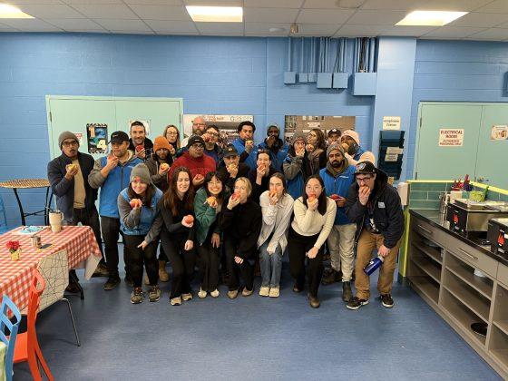 large group of staff members posing and biting into an apple together for the Great Big Crunch