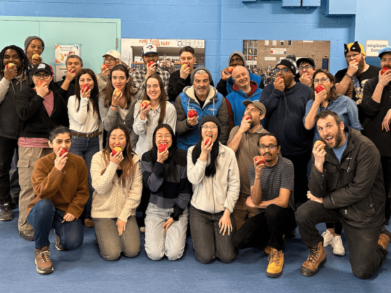 large group of staff members posing and biting into an apple together for the Great Big Crunch