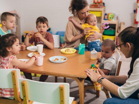 children have breakfast in kindergarten with caregivers
