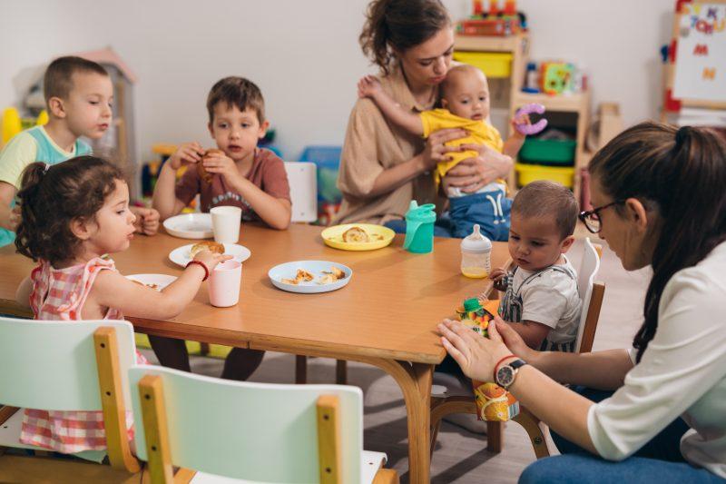 children have breakfast in kindergarten with caregivers