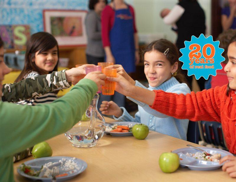 school kids at lunch table, cheers with their water cups