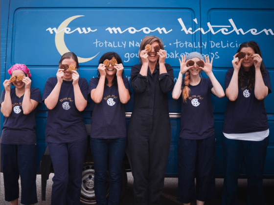 6 women standing in front of New Moon Kitchen van having fun smiling for photo