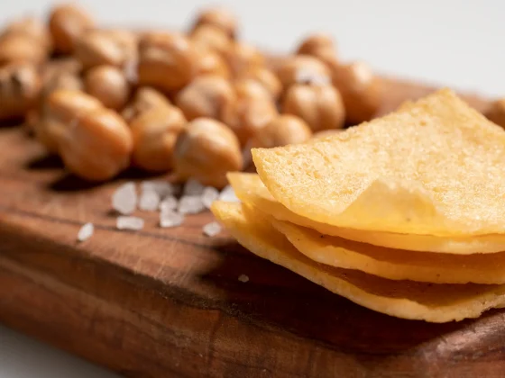 close up view of Peacasa chickpea chips on a cutting board with light sprinkle of salt and portion of chickpeas next to them