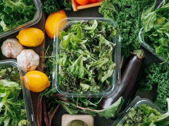 open package of fresh vision greens surrounded by other produce