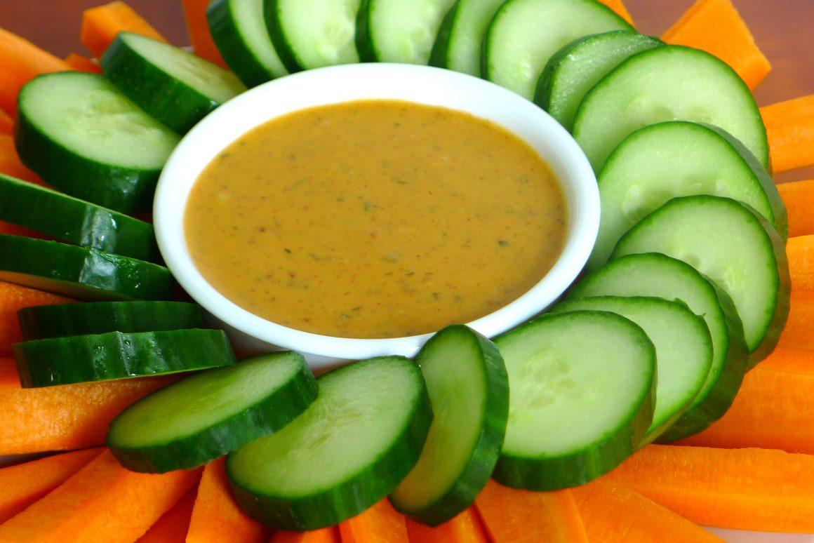 small white bowl of custom RFRK-made maple samurai vinaigrette surrounded by a circle of cucumber slices and carrot sticks