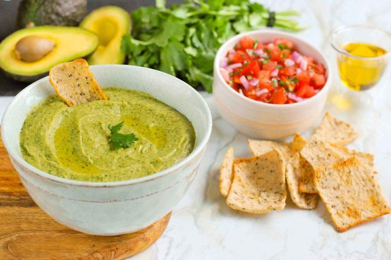 Avocado Bean Guacamole in a bowl with multigrain and chia crisps