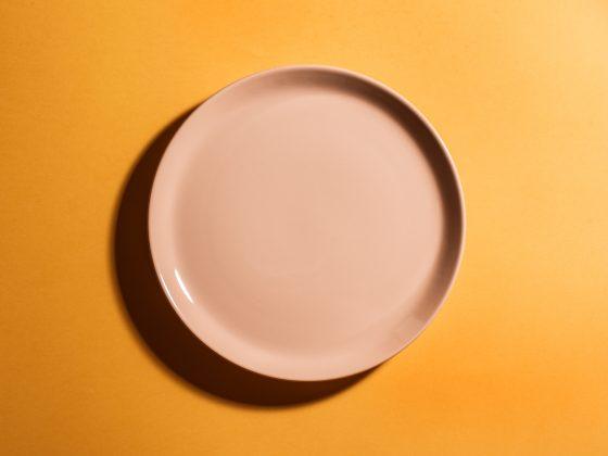 Orange empty plate on orange background