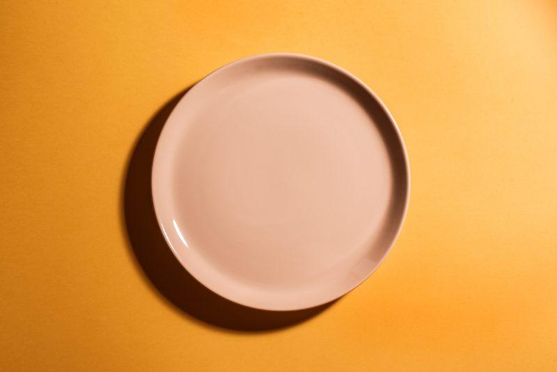 Orange empty plate on orange background