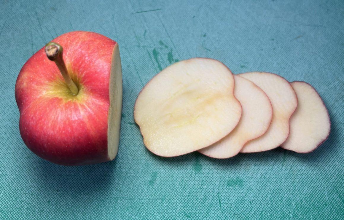 sliced apples next to half full apple on blue cutting board