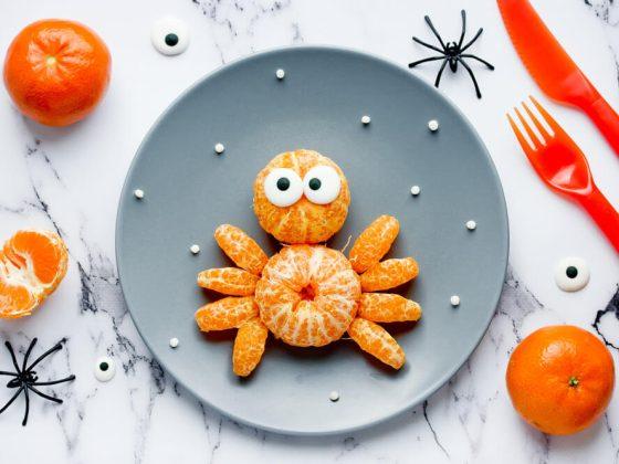 spider snack made with tangerines arranged in the shape of a spider on a gray plate