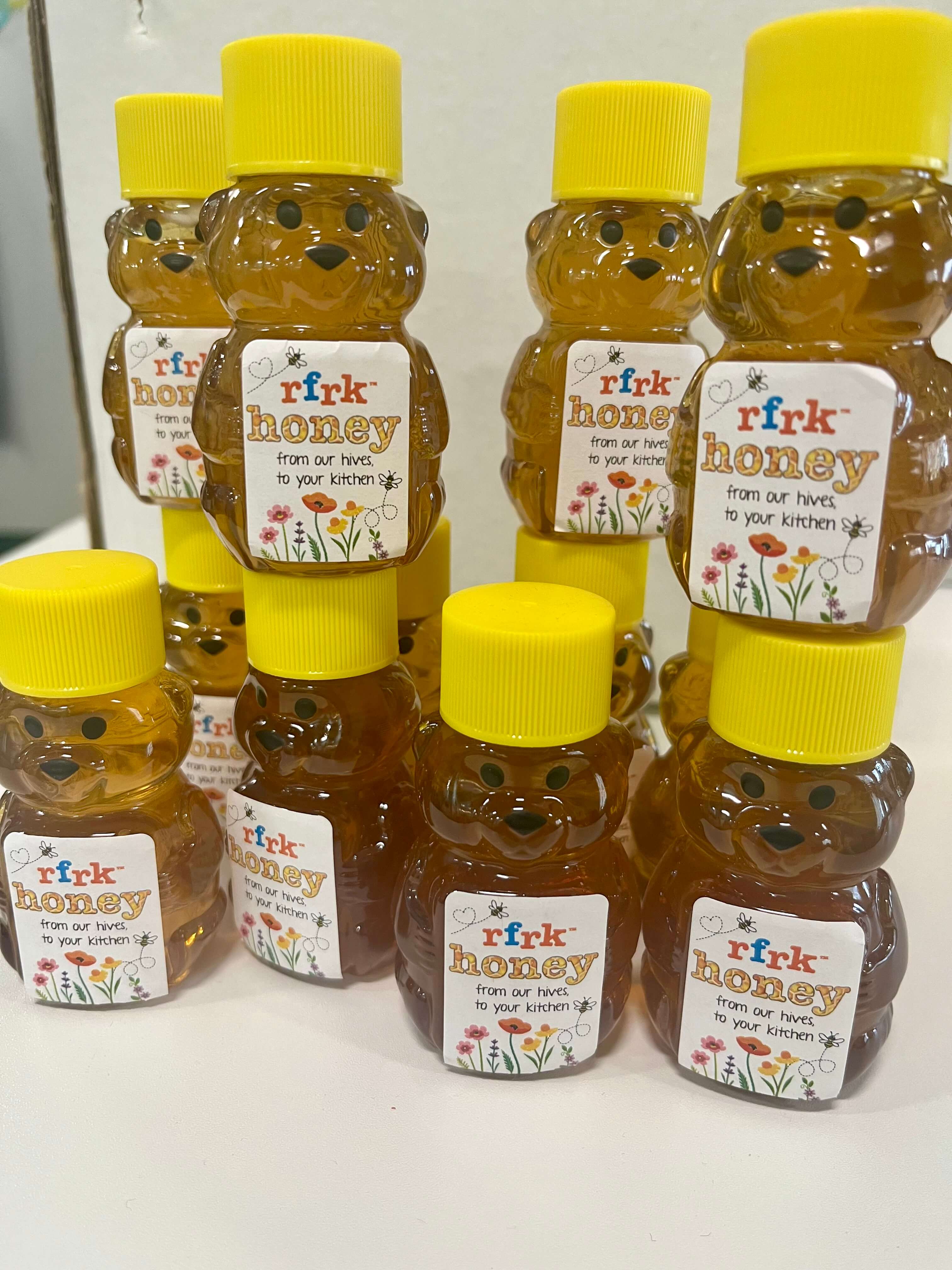 jars of hyper local toronto honey, around 8 jars, with bear shapes and yellow tops and RFRK honey label printed on front stacked together